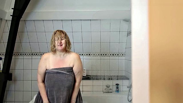 La matrigna matura e tettona si sditalina sotto la doccia