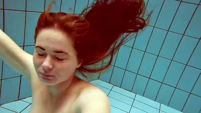 Lola, a girl with big natural tits, swims underwater.